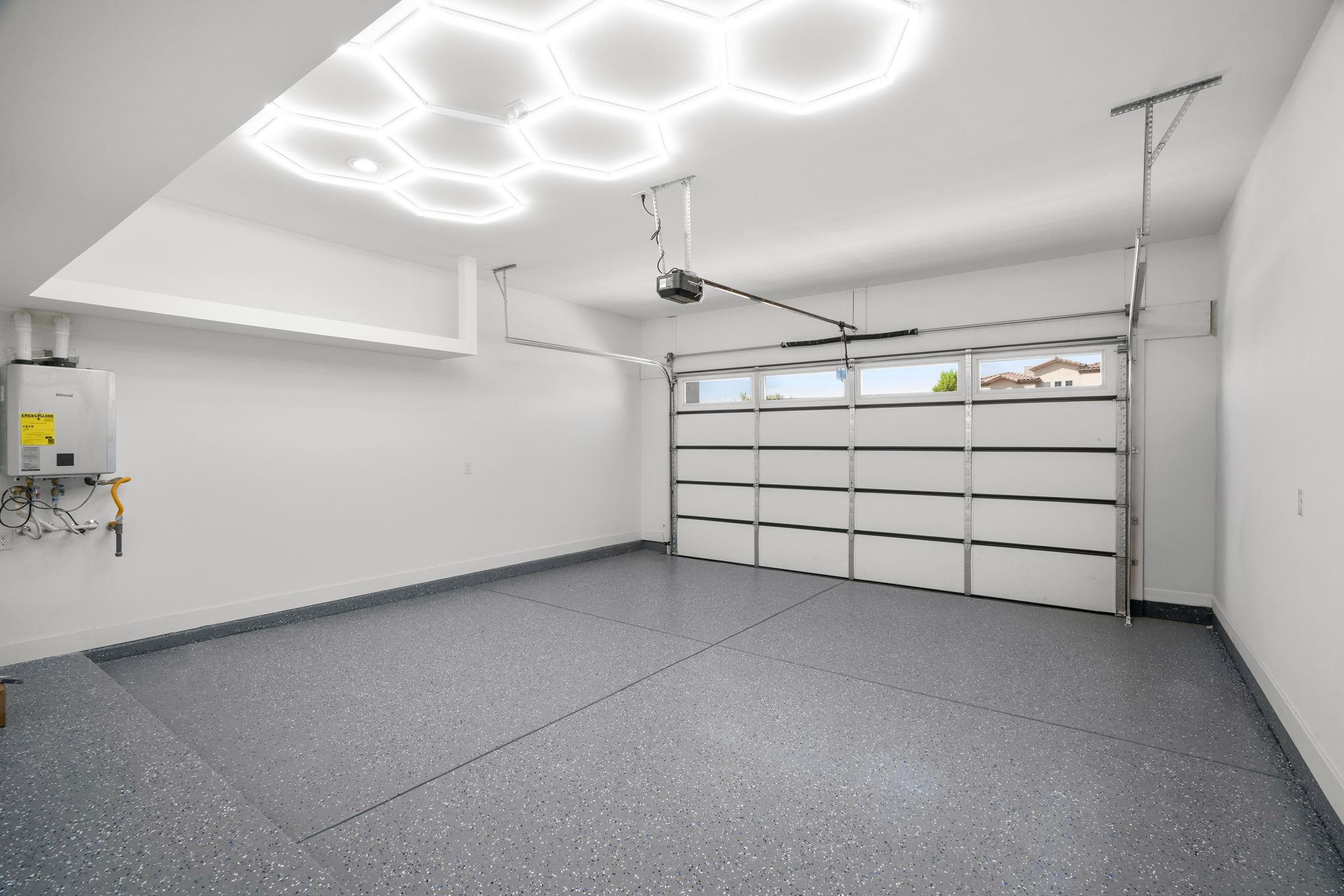 Vacant garage with speckled epoxy flooring and illuminated geometric ceiling panels.