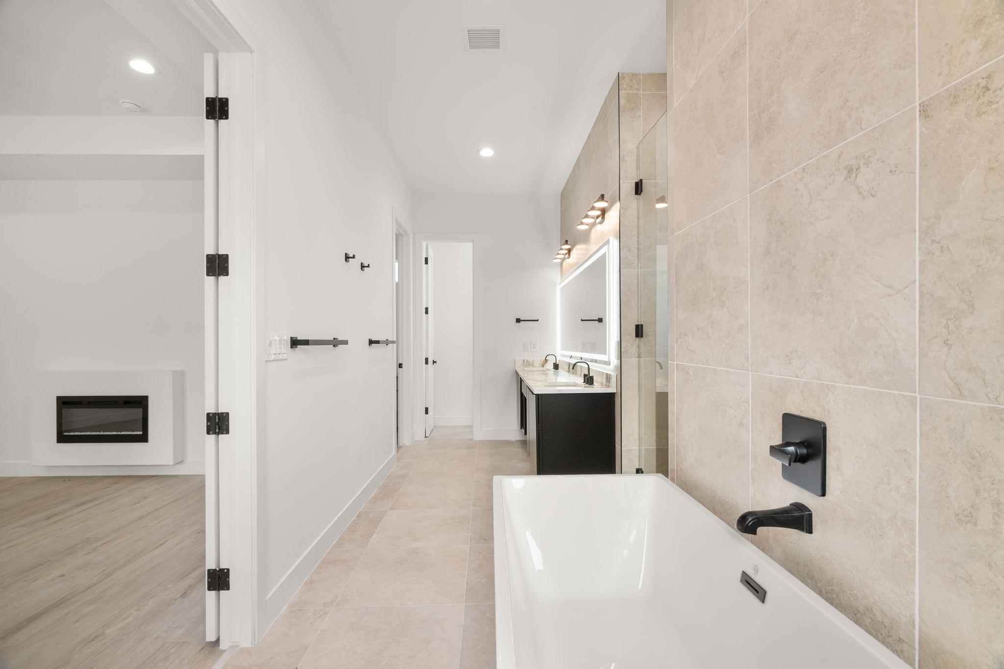 Modern bathroom with a freestanding tub, glass shower, and dark double vanity.