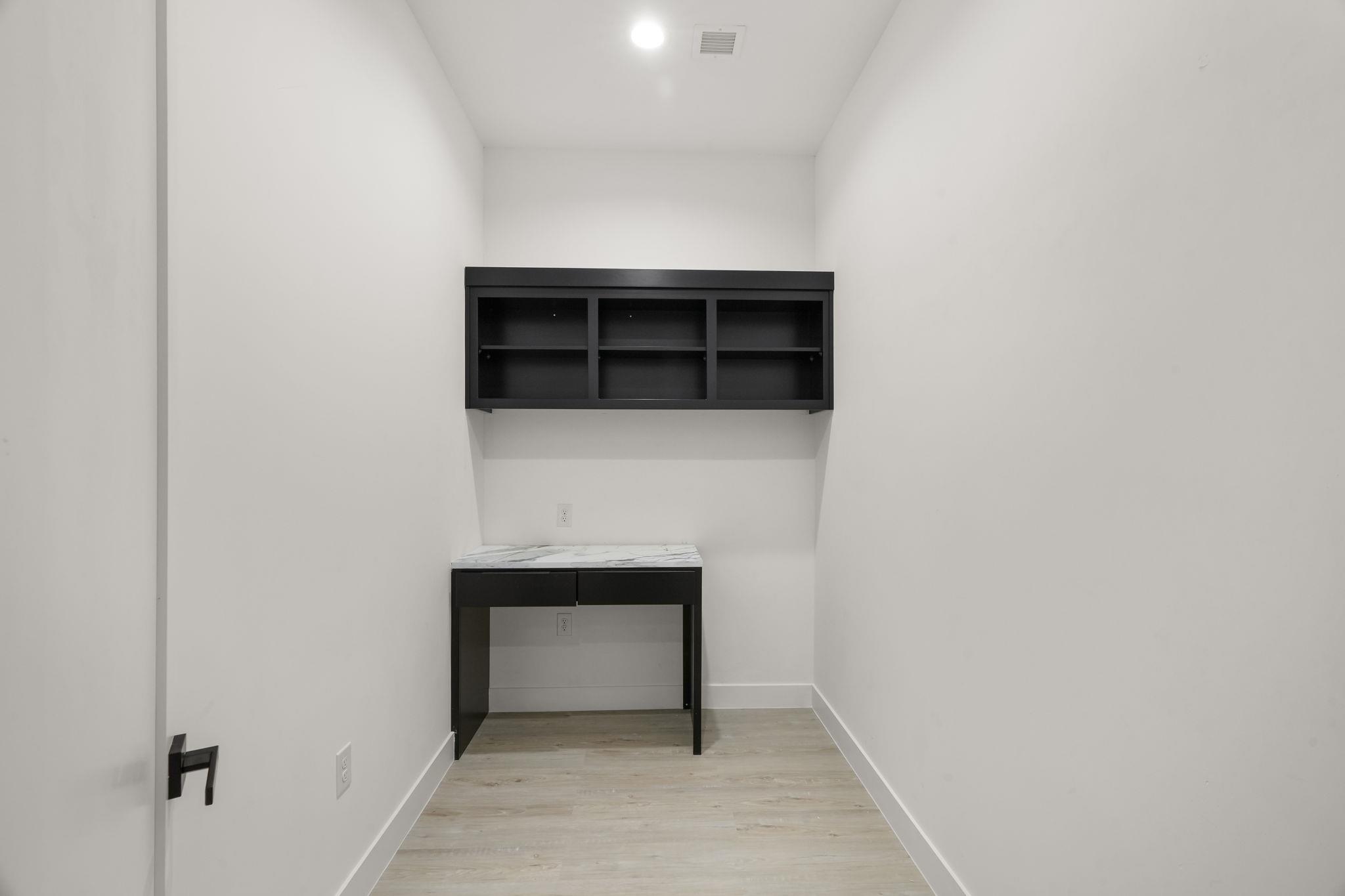Compact office nook with a black desk and matching wall-mounted shelves.