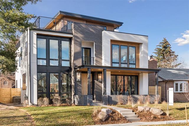 Modern two-story house with dark brick, large windows, and a rooftop terrace.