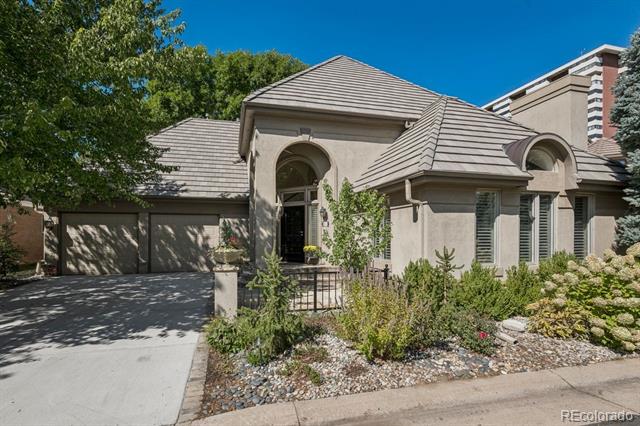 Stucco home with an arched entry, attached garage, and landscaped rock garden.