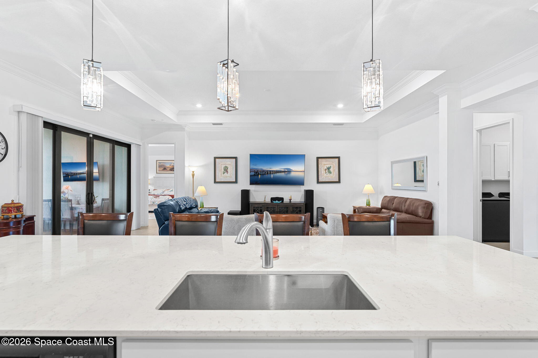 Kitchen island with a white stone countertop and sink overlooking a furnished living area.