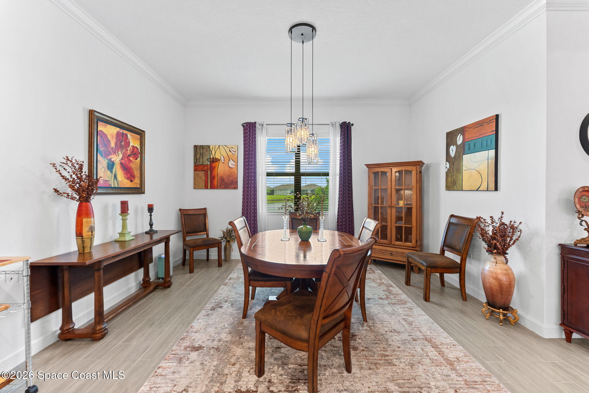 Dining room with an oval wooden table, matching chairs, and a glass-front cabinet.