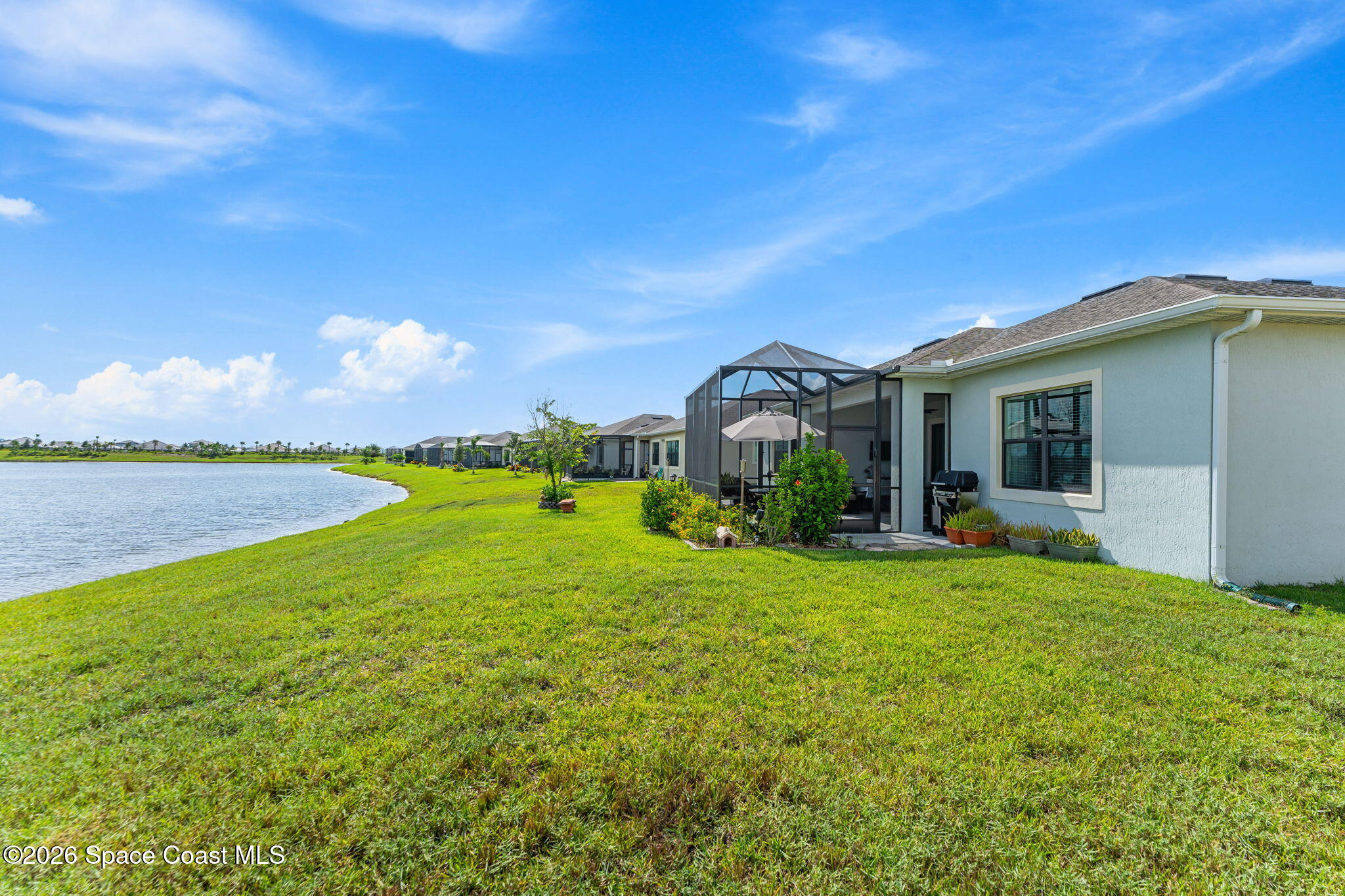 Home’s screened lanai and grassy backyard overlook a lake.