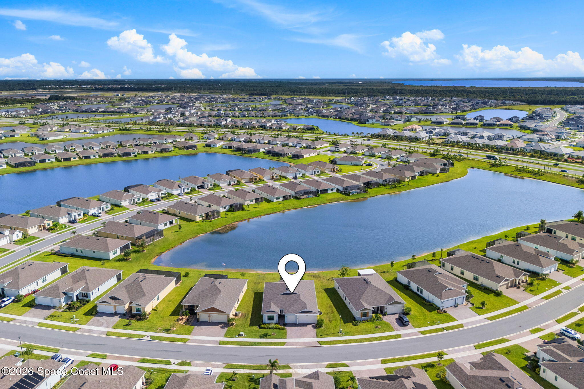 Aerial view of the marked home beside a pond in a sprawling neighborhood.