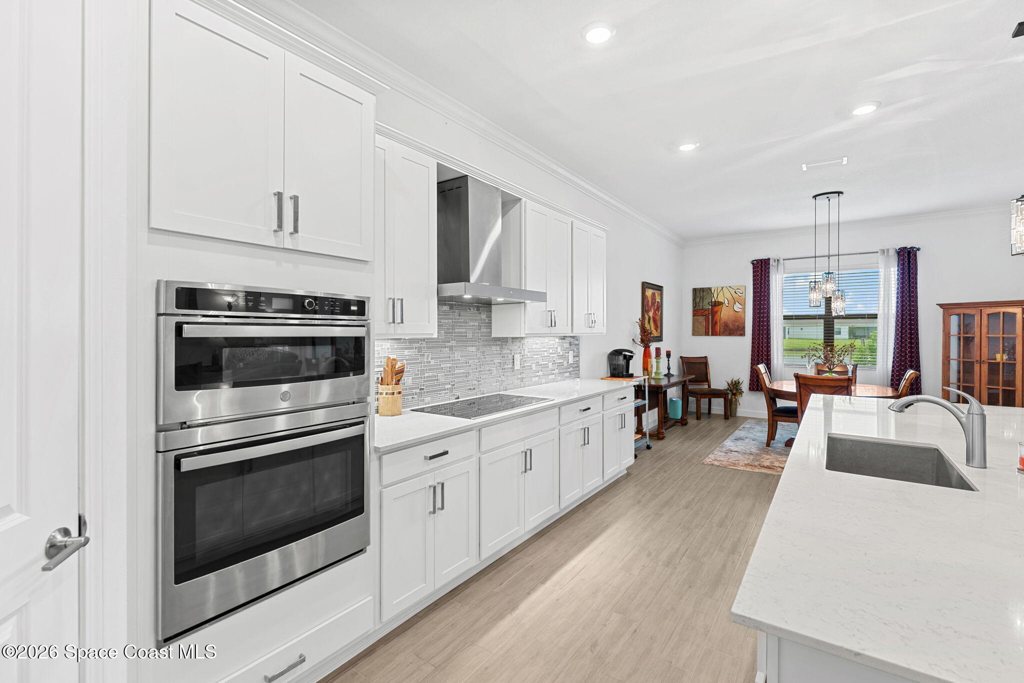 Bright kitchen with white shaker cabinets, double wall ovens, and a large island overlooking the dining area.