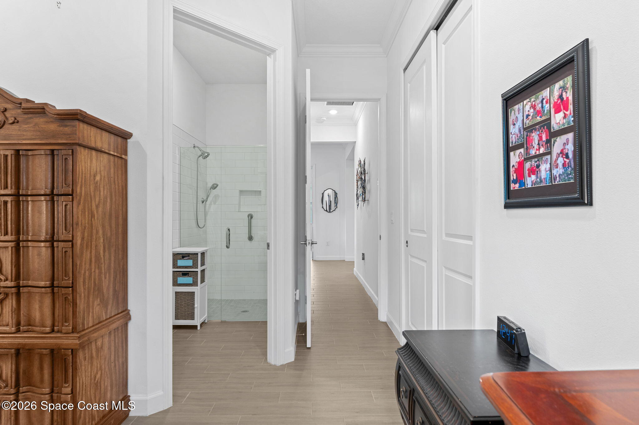 Bright hallway with a tiled walk-in shower visible through an open doorway and a carved wooden cabinet.