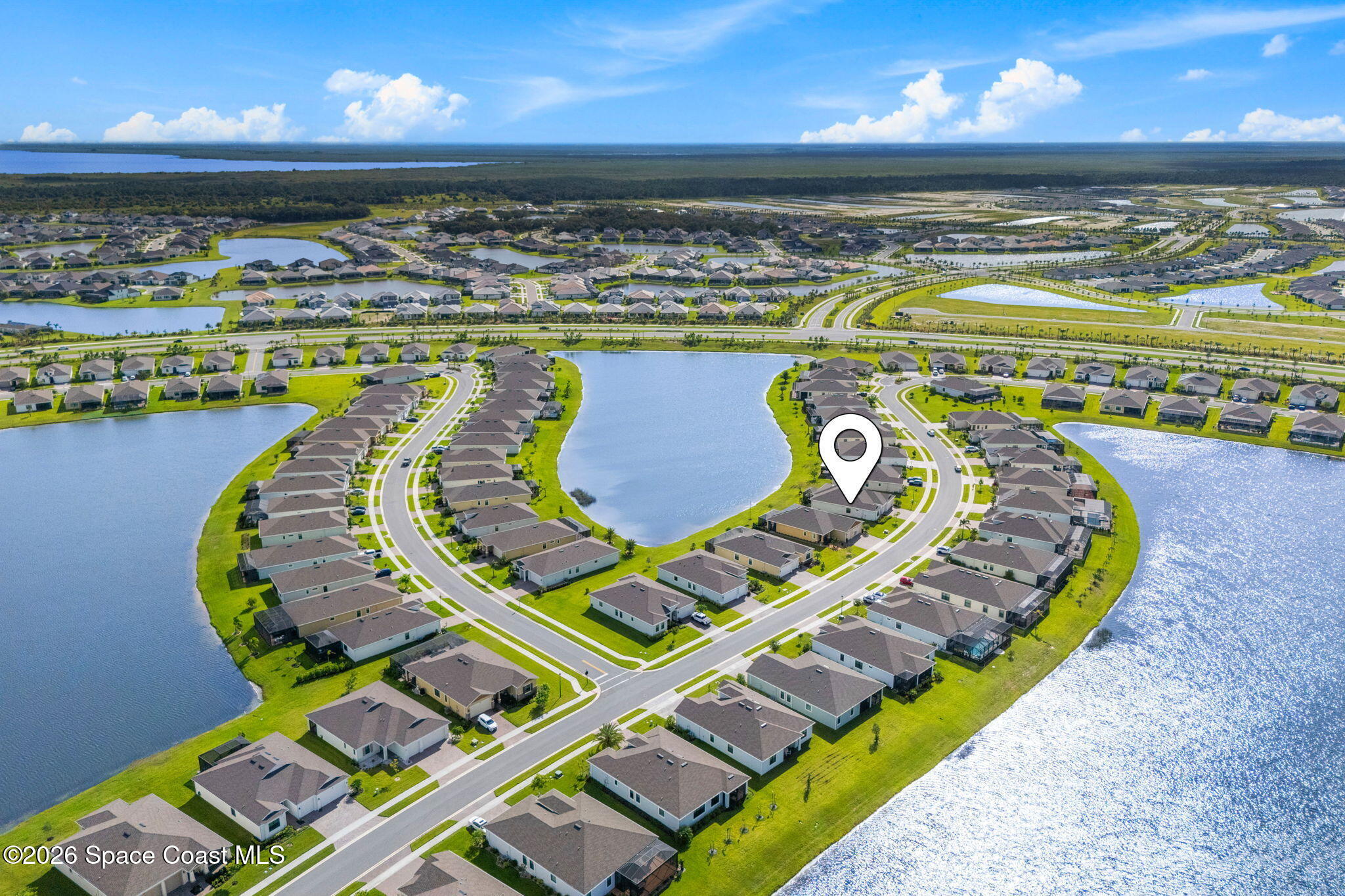 Aerial view of a lakeside neighborhood, with a map pin marking one home.
