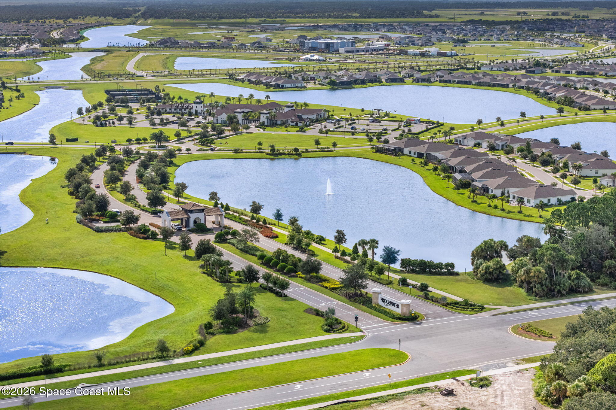 Aerial view of Bridgewater homes around lakes, with a fountain and landscaped entrance.