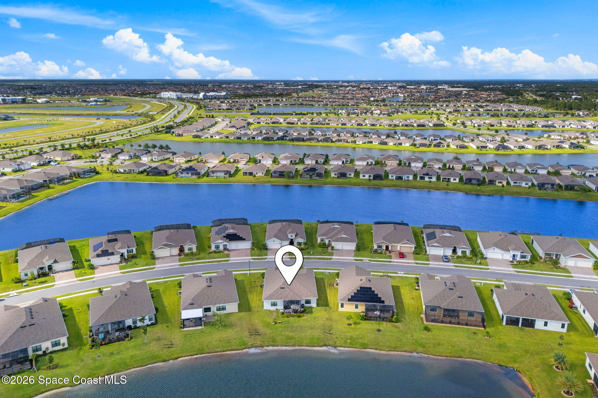 Aerial view of a home beside a lake in a residential community, marked by a location pin.