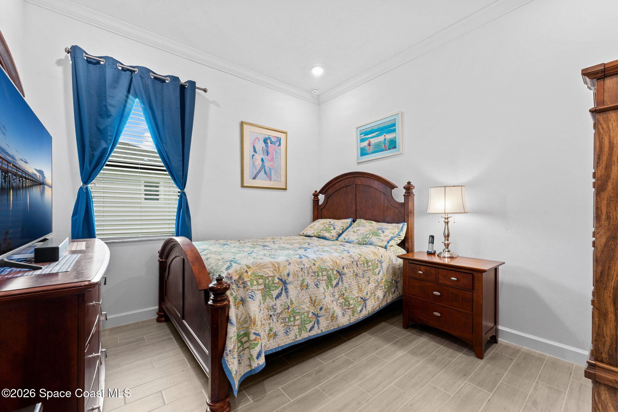 Bedroom with a dark wood bed, floral quilt, and bright blue curtains.