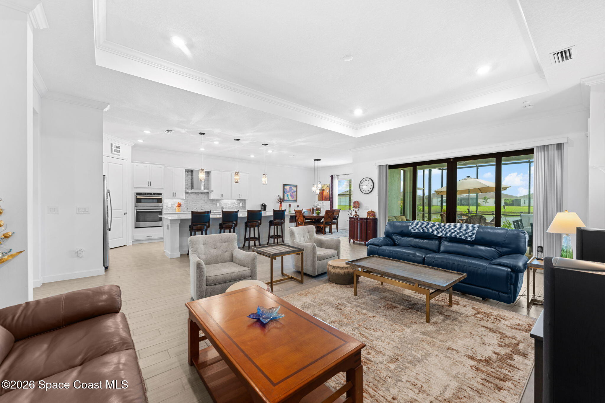 Open-plan living room with blue sofa, white kitchen island, and sliding doors to a covered patio.