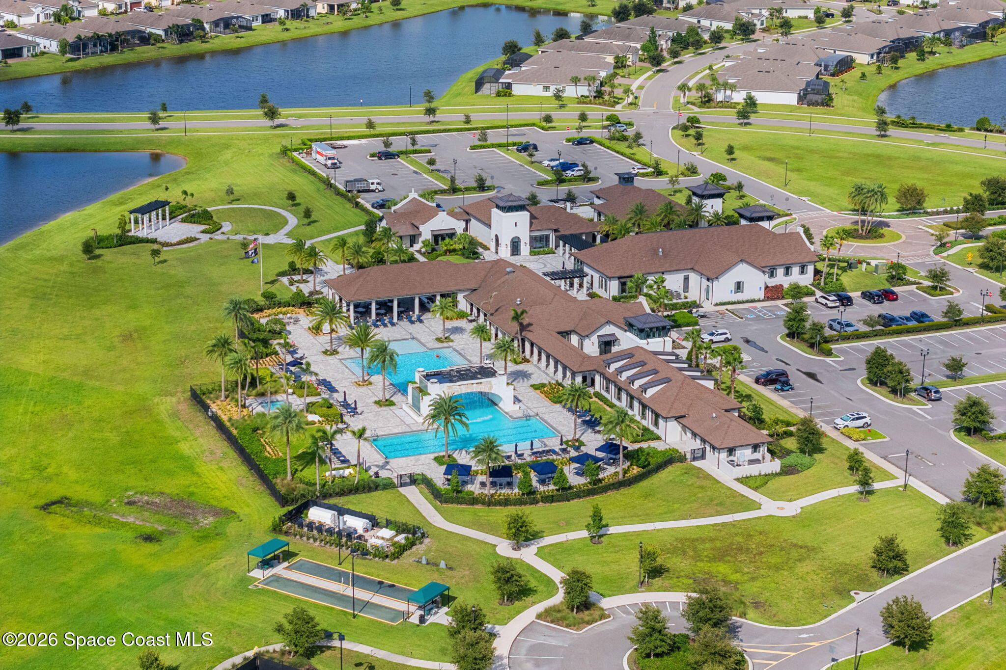 Community clubhouse with two swimming pools and landscaped grounds beside a lake.