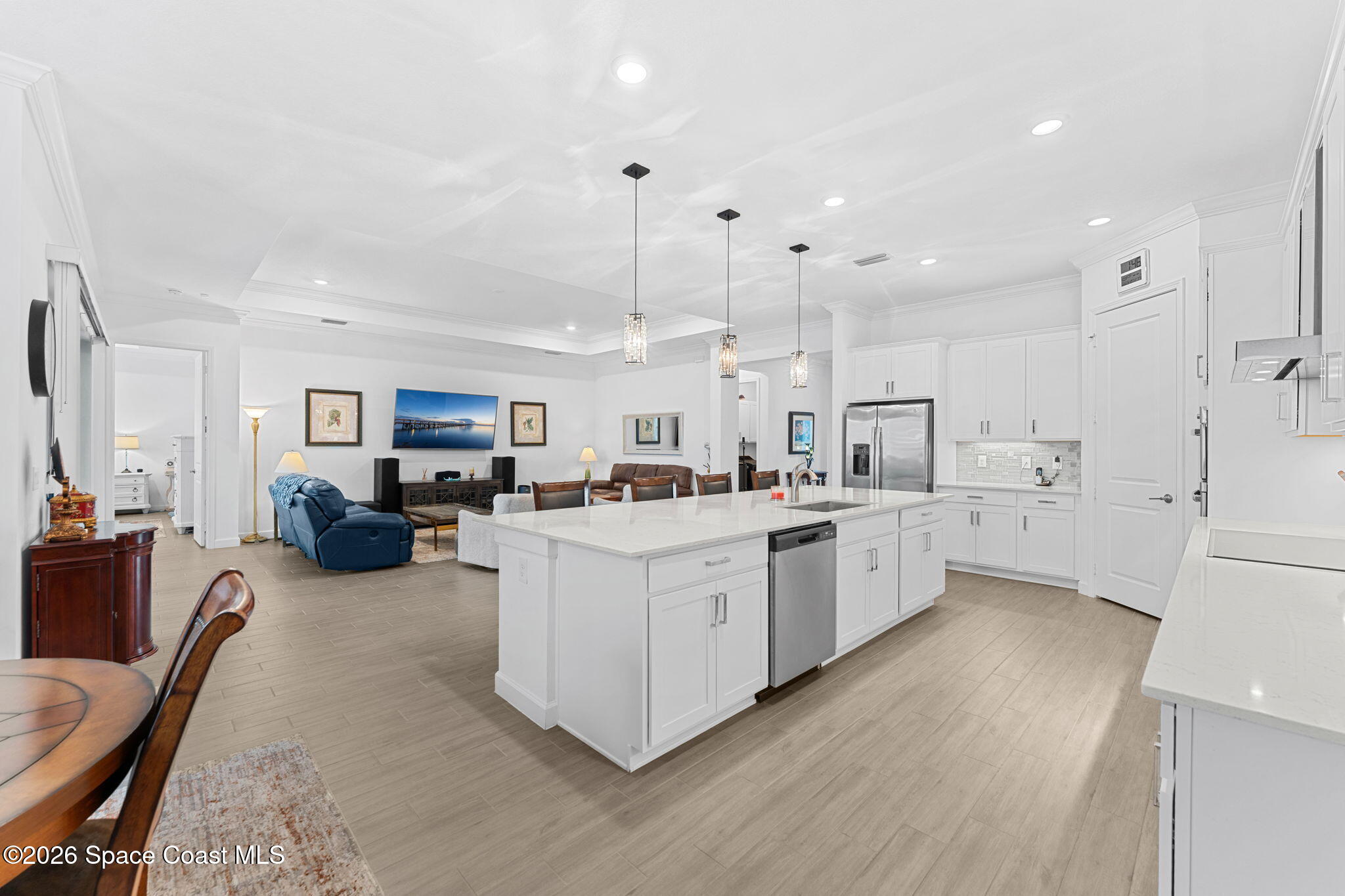Open-plan kitchen and living room with a large white island and blue recliner.