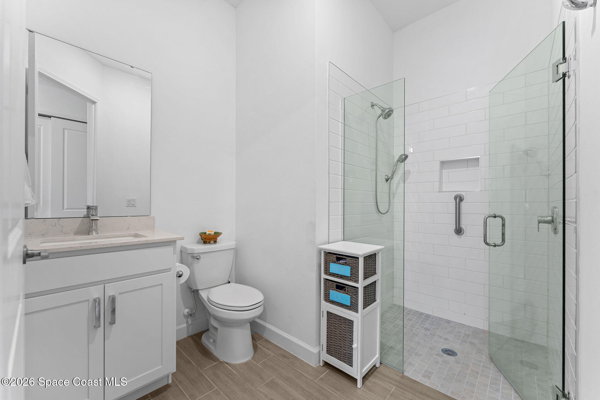 Bathroom with a glass walk-in shower, white subway tile, dual showerheads, and a white vanity.