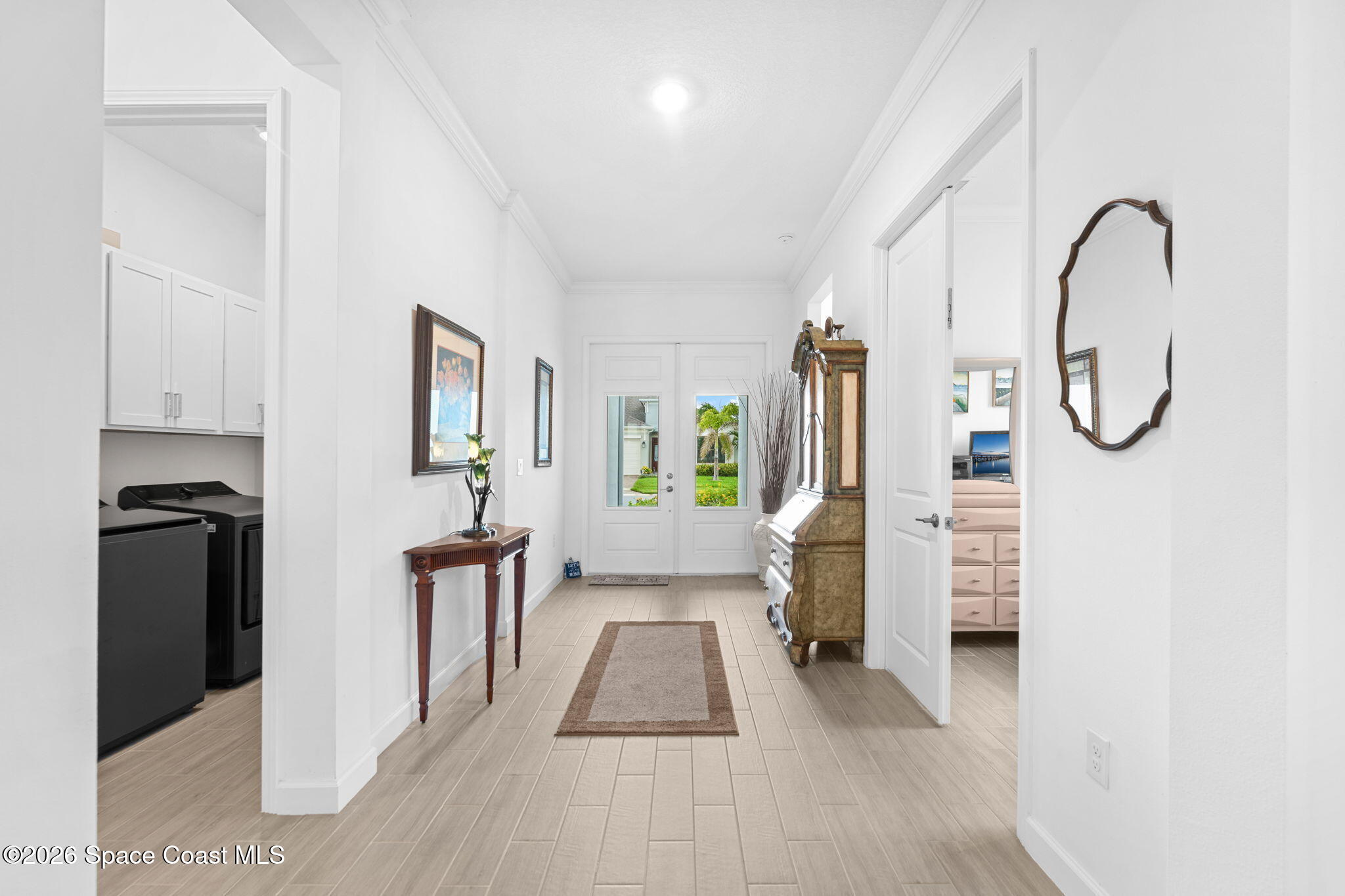 Bright tiled entry foyer with glass-paneled double doors and a laundry area to the left.