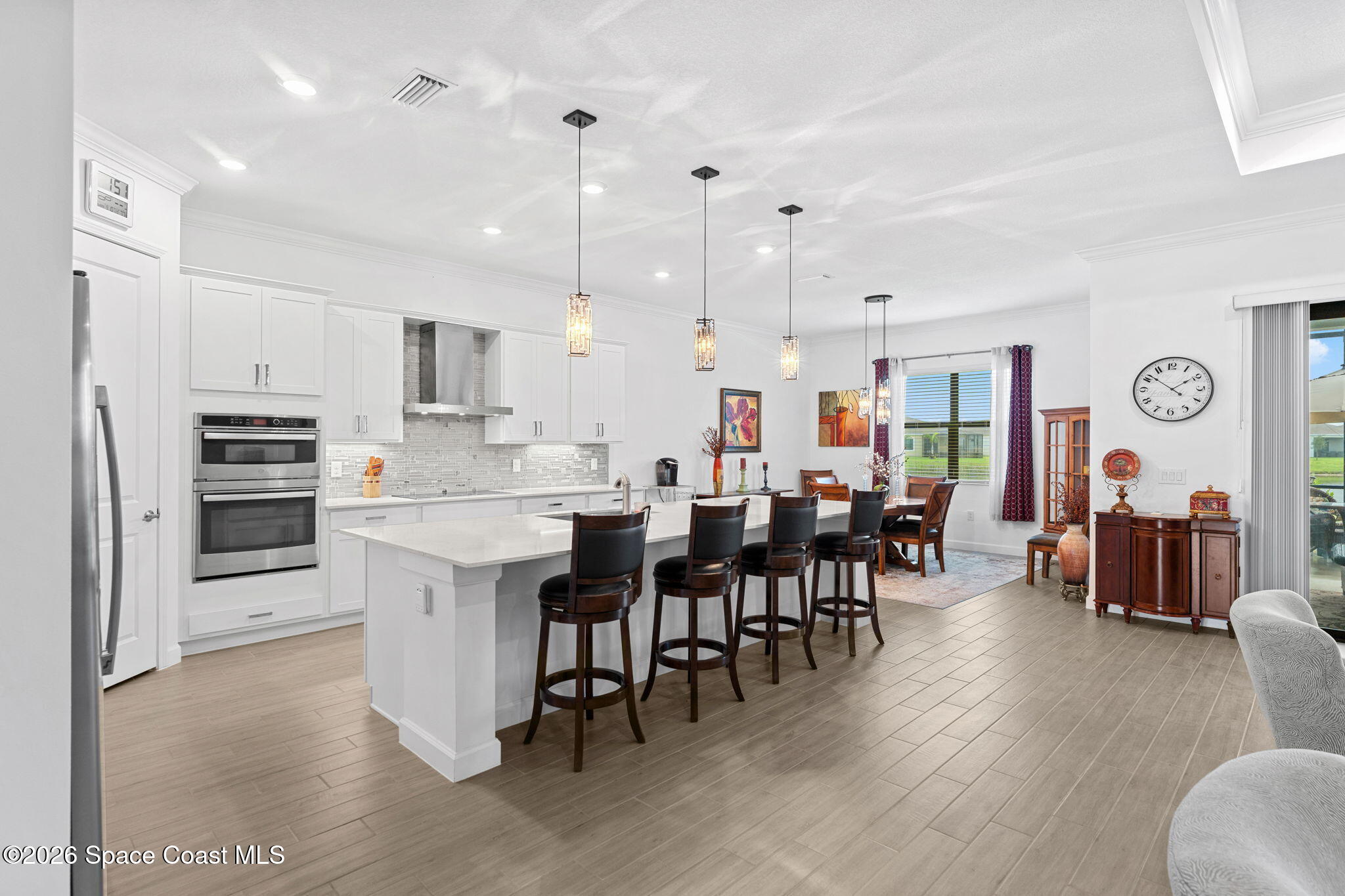 Open-plan kitchen and dining area with a large island, dark bar stools, and white cabinetry.