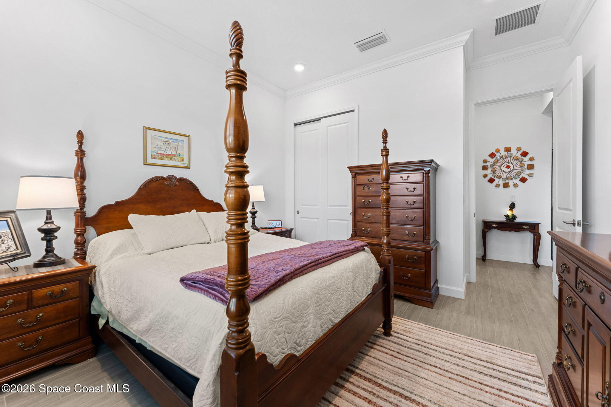 Bedroom with a dark wood four-poster bed, white quilted bedding, and a purple throw.