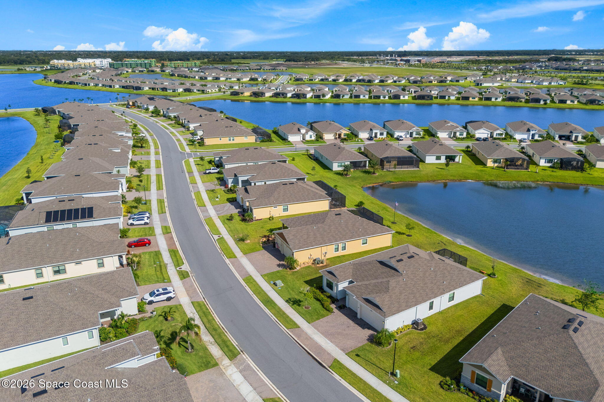 Aerial view of homes lining a neighborhood street beside lakes.