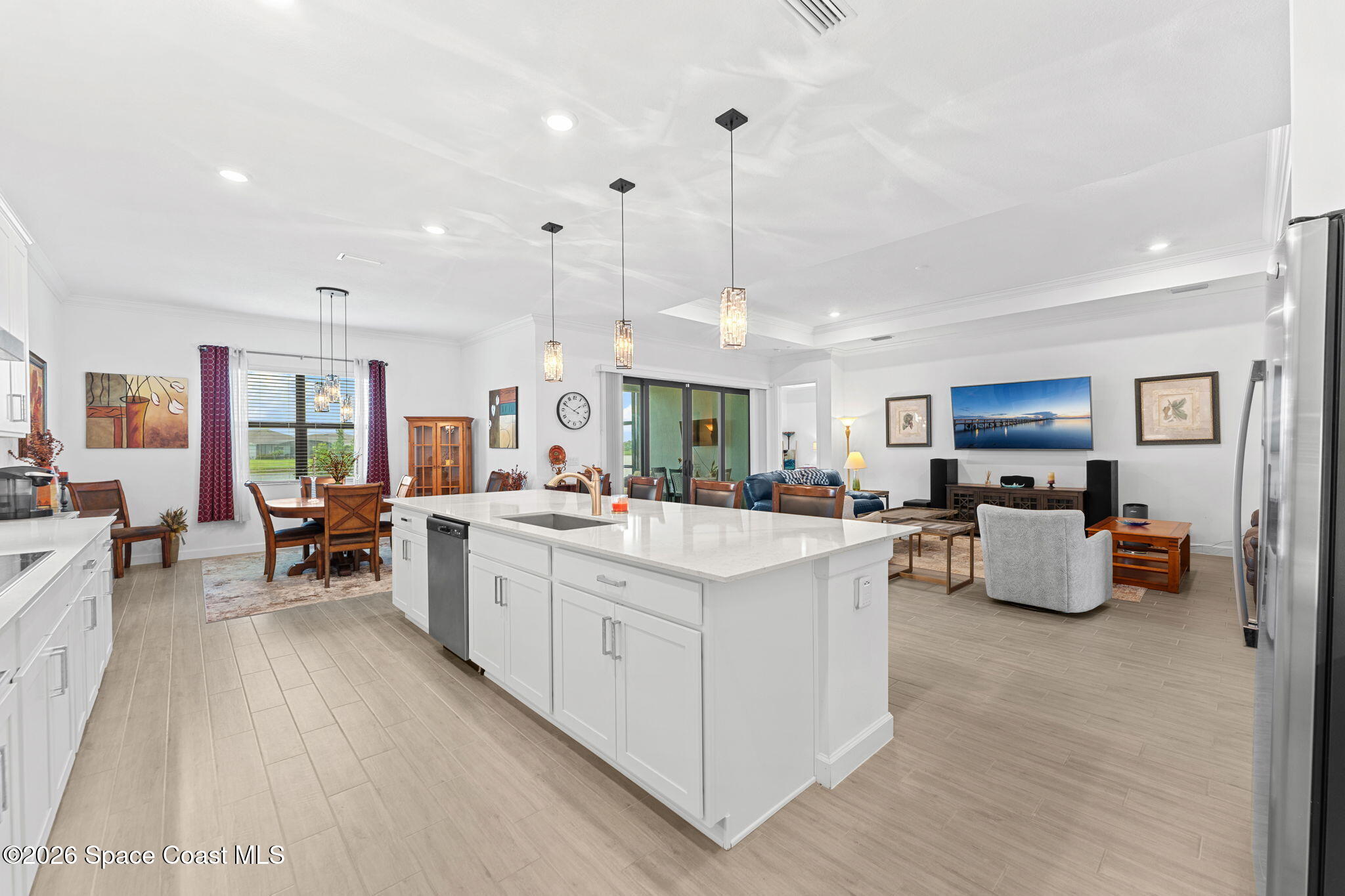 Open-plan kitchen and living room with a large white island and three pendant lights.
