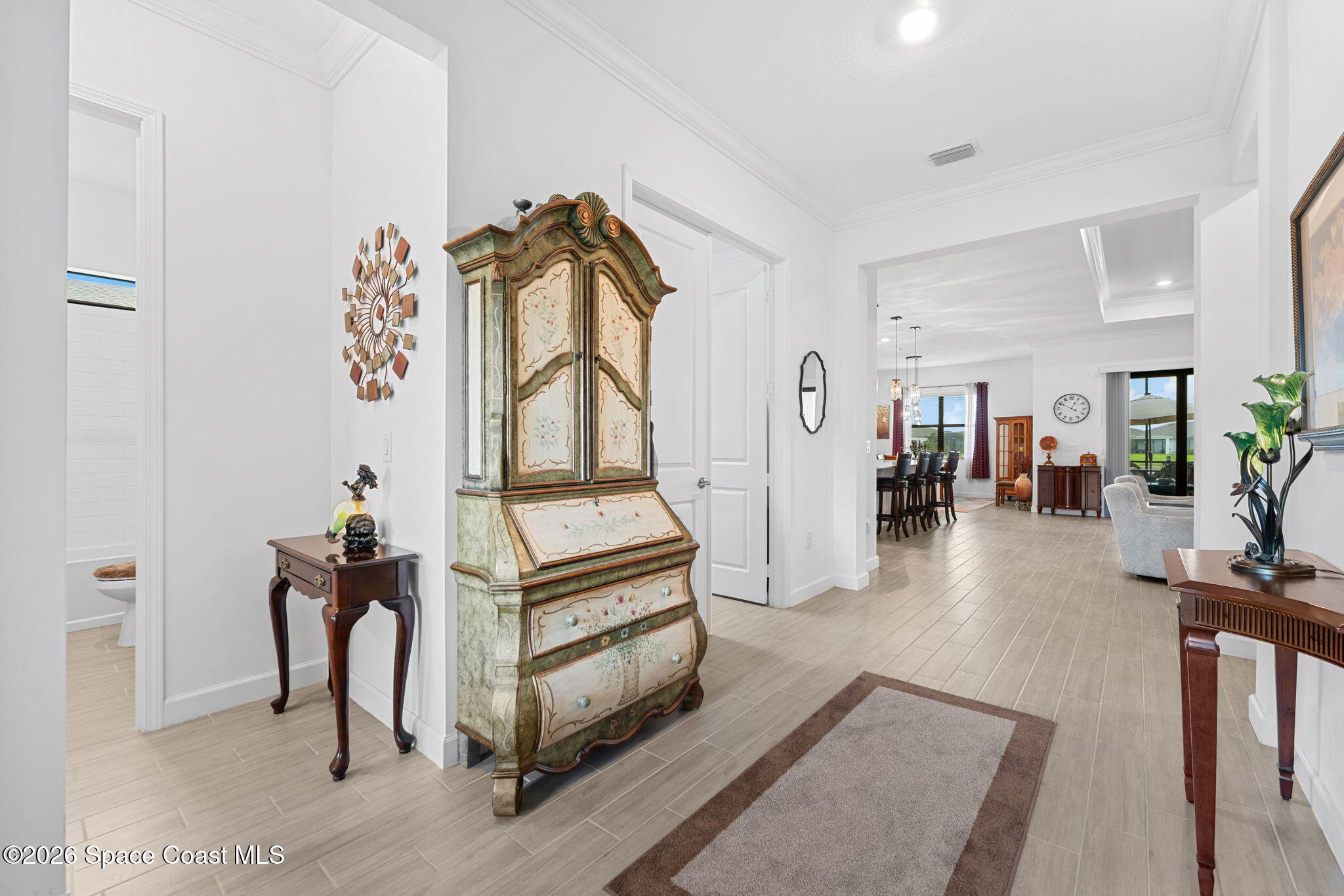 Furnished entry foyer with an ornate painted armoire and views into the dining and living areas.