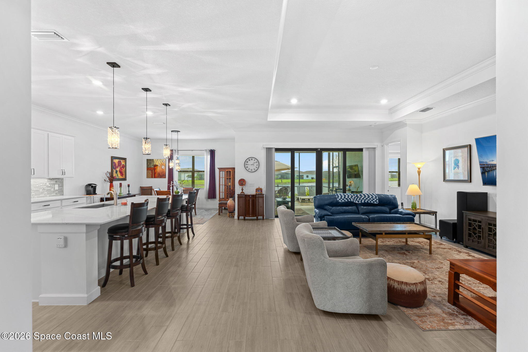 Open-plan kitchen and living room with a white island, blue sofa, and lake views through sliding doors.