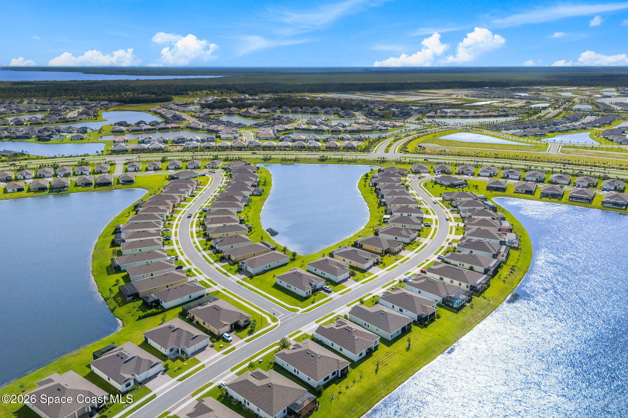 Aerial view of a residential neighborhood with curving streets, rows of homes, and multiple lakes.