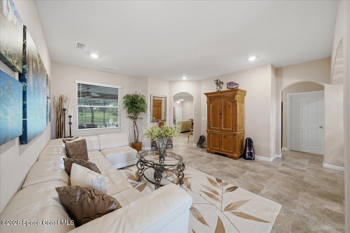 Furnished living room with a white sectional, glass coffee table, and ornate wooden armoire.