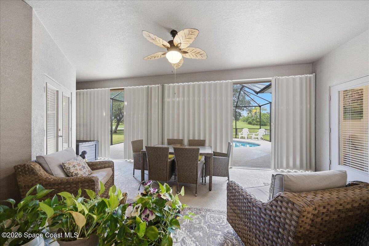 Furnished sunroom with wicker seating and dining table overlooking a screened pool patio.