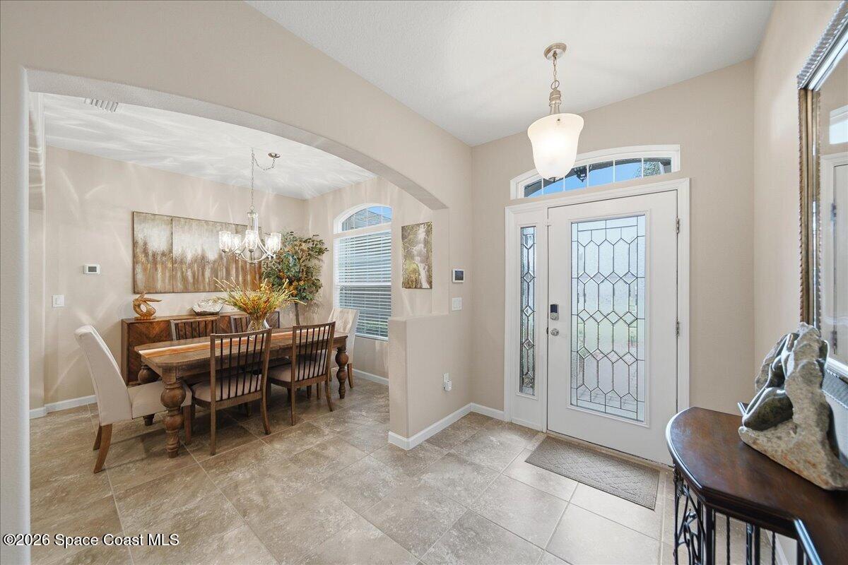 Furnished entryway with a glass-panel front door opening to a dining room through a wide arch.