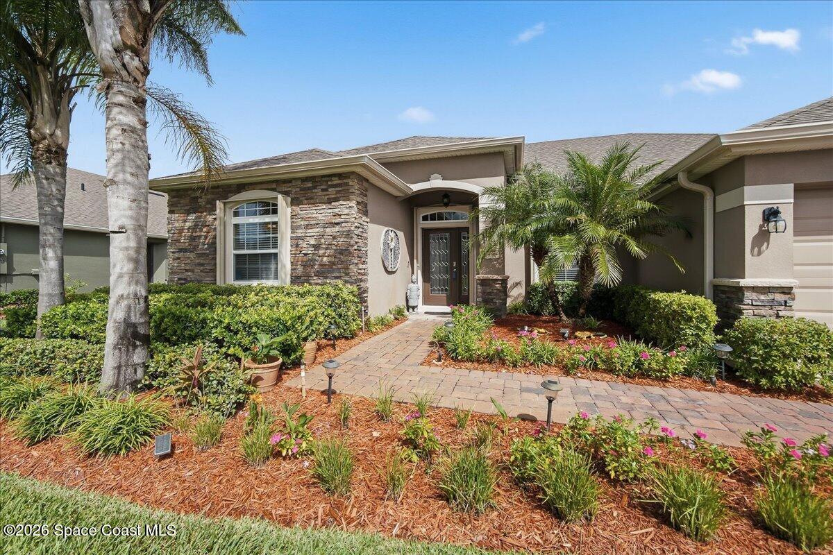 Single-story home with stone accents, a covered entry, and a landscaped paver walkway.