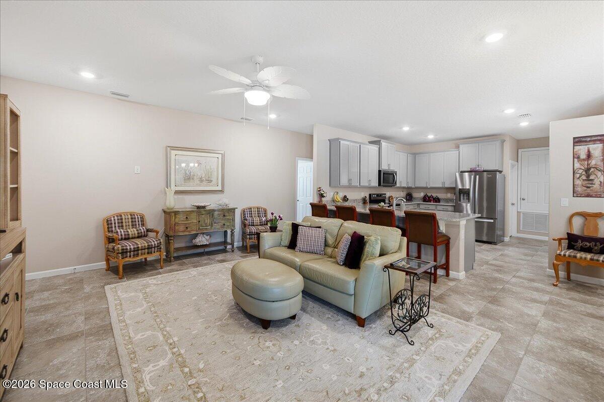 Open-plan living room and kitchen with gray cabinetry, stainless appliances, and a furnished seating area.
