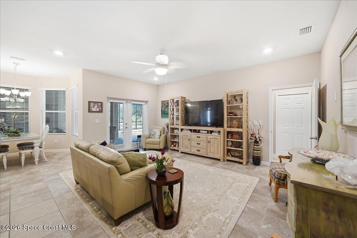 Furnished living room with beige seating, tiled floors, and sliding glass doors.