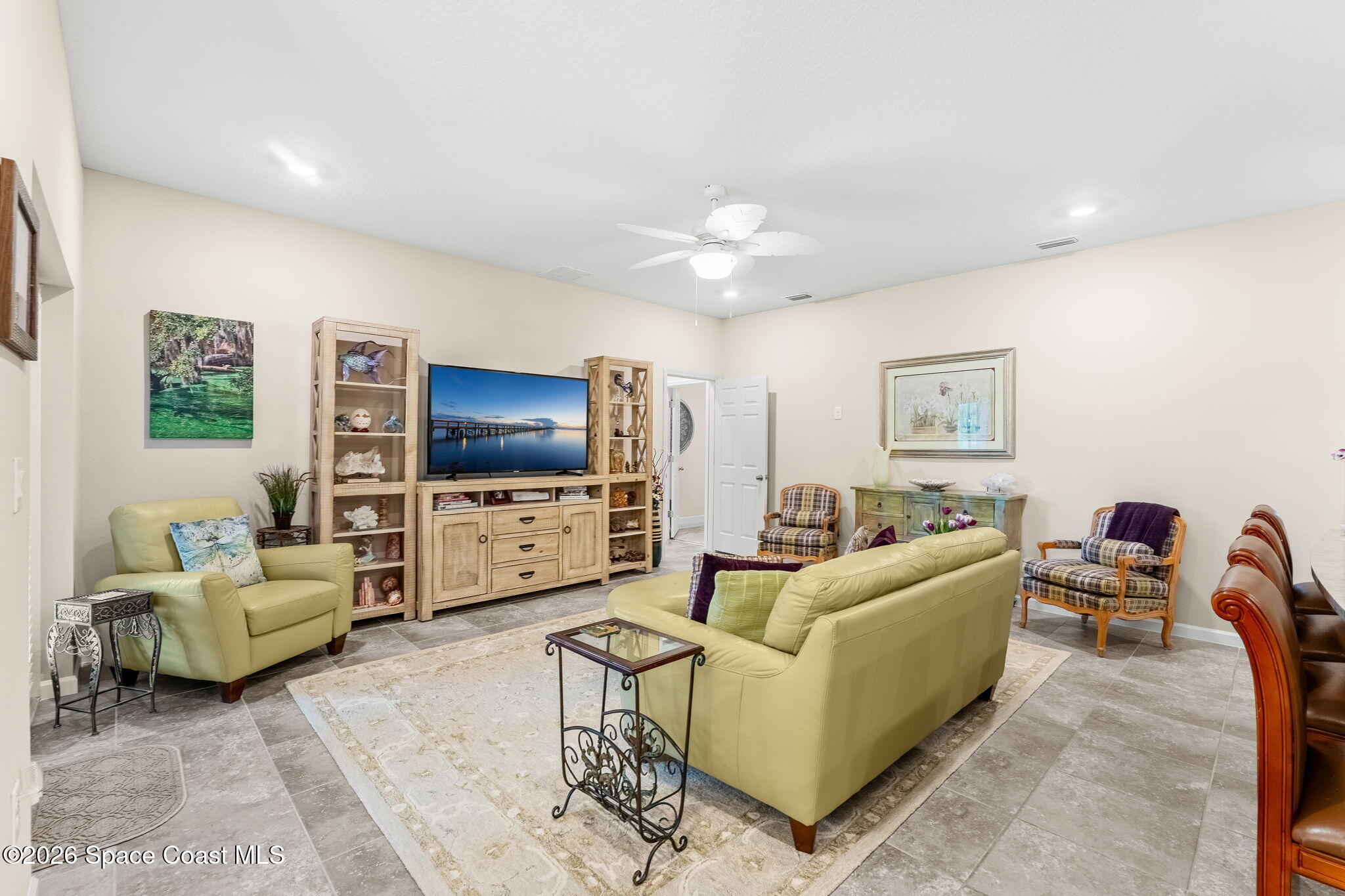 Furnished living room with pale green seating, plaid accent chairs, and a wood entertainment center.