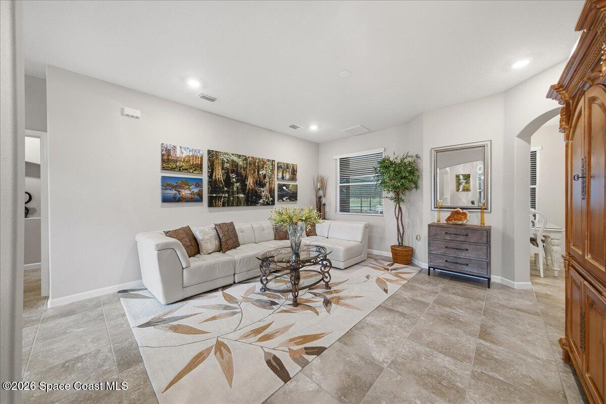 Living room with a white sectional, botanical artwork, and a large leaf-patterned rug.