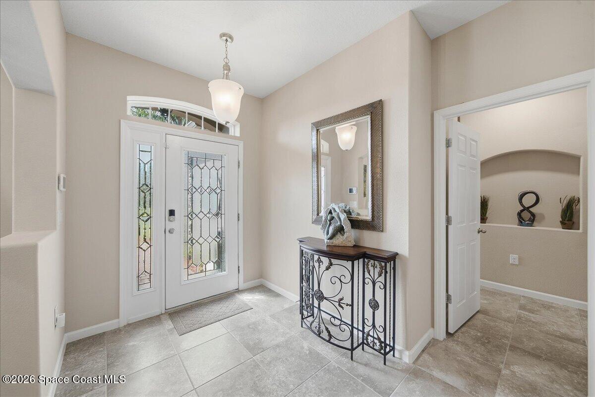 Entry foyer with a glass-paneled front door, tiled floor, and decorative console table.