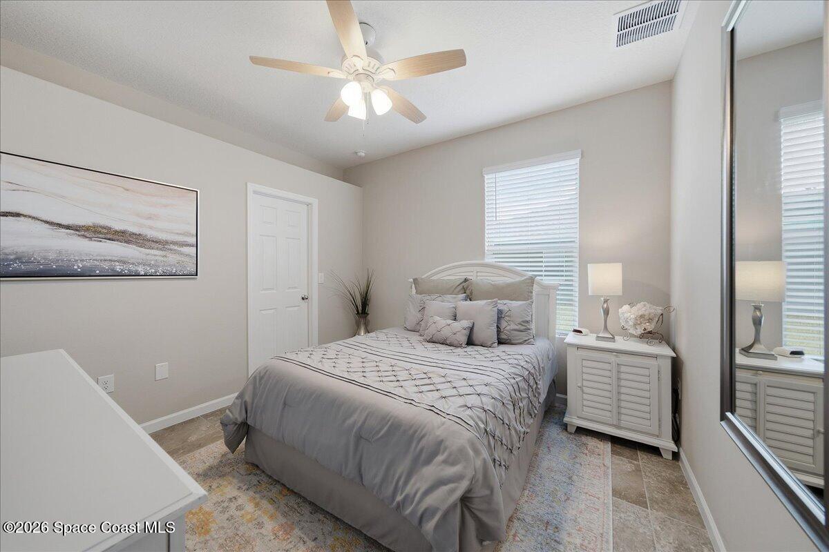 Bedroom with a gray bed, white nightstand, ceiling fan, and mirrored closet door.