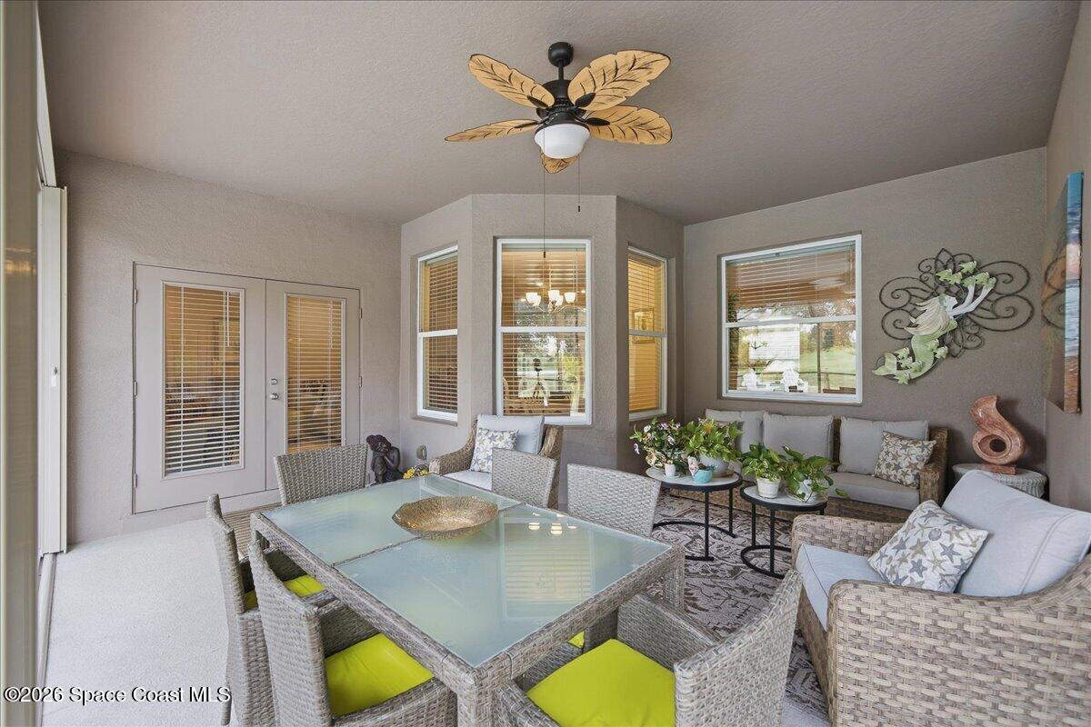 Enclosed patio with wicker dining set, cushioned seating, large windows, and a ceiling fan.
