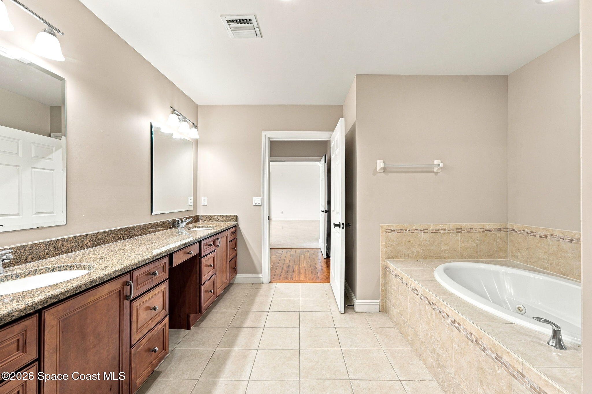 Bathroom with a long granite-topped vanity and a built-in soaking tub.