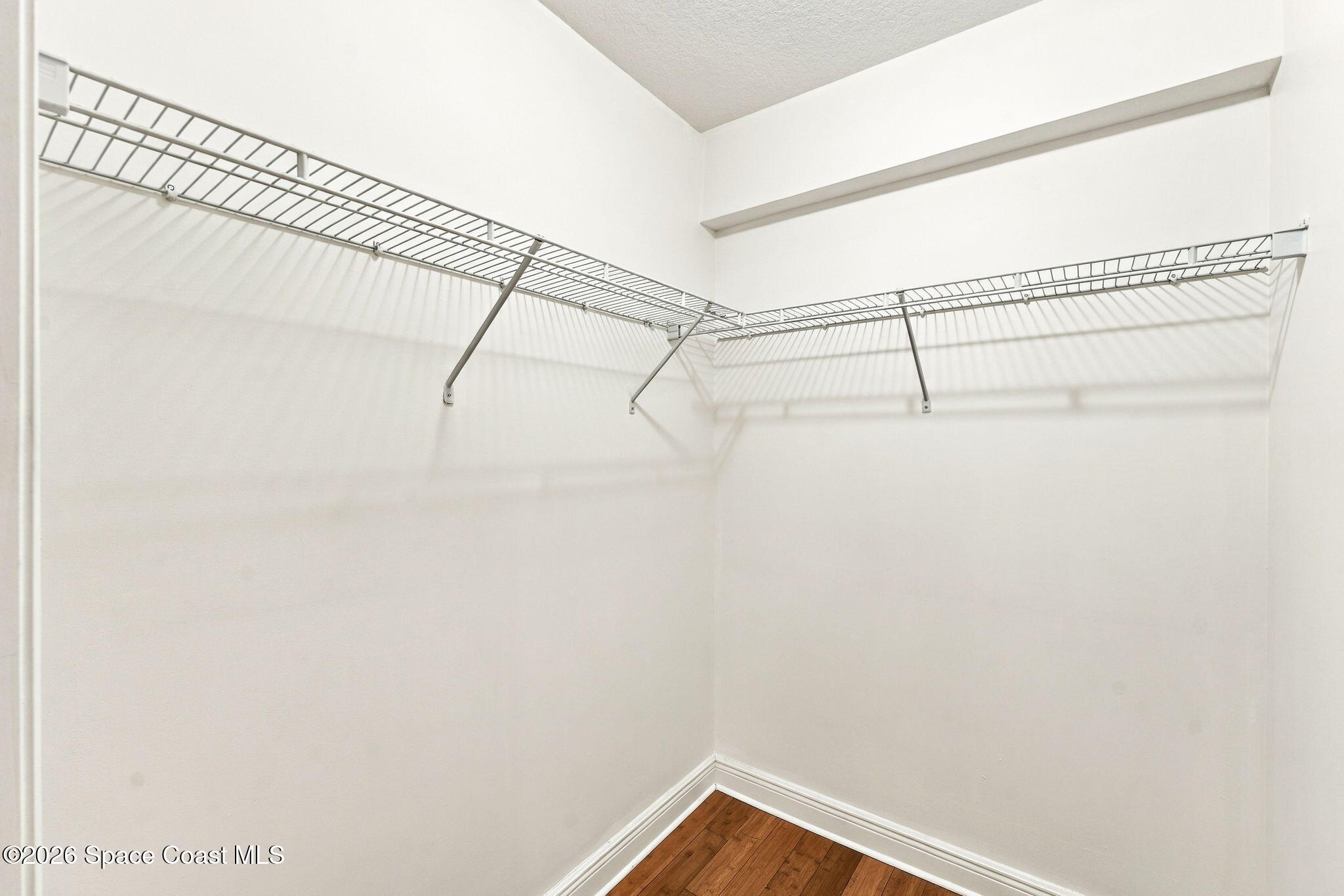 Walk-in closet with wraparound wire shelves and hardwood flooring
