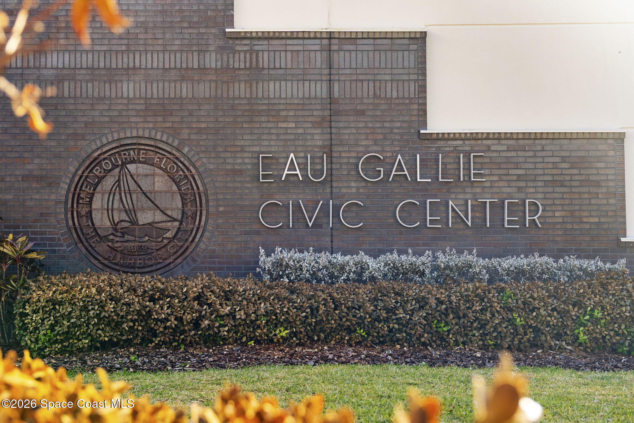 Eau Gallie Civic Center sign and City of Melbourne seal above landscaped hedges.