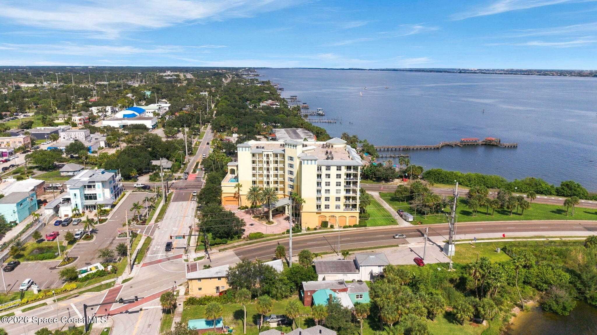 Waterfront condominium beside a long pier, seen from above with the Melbourne shoreline and waterway beyond.
