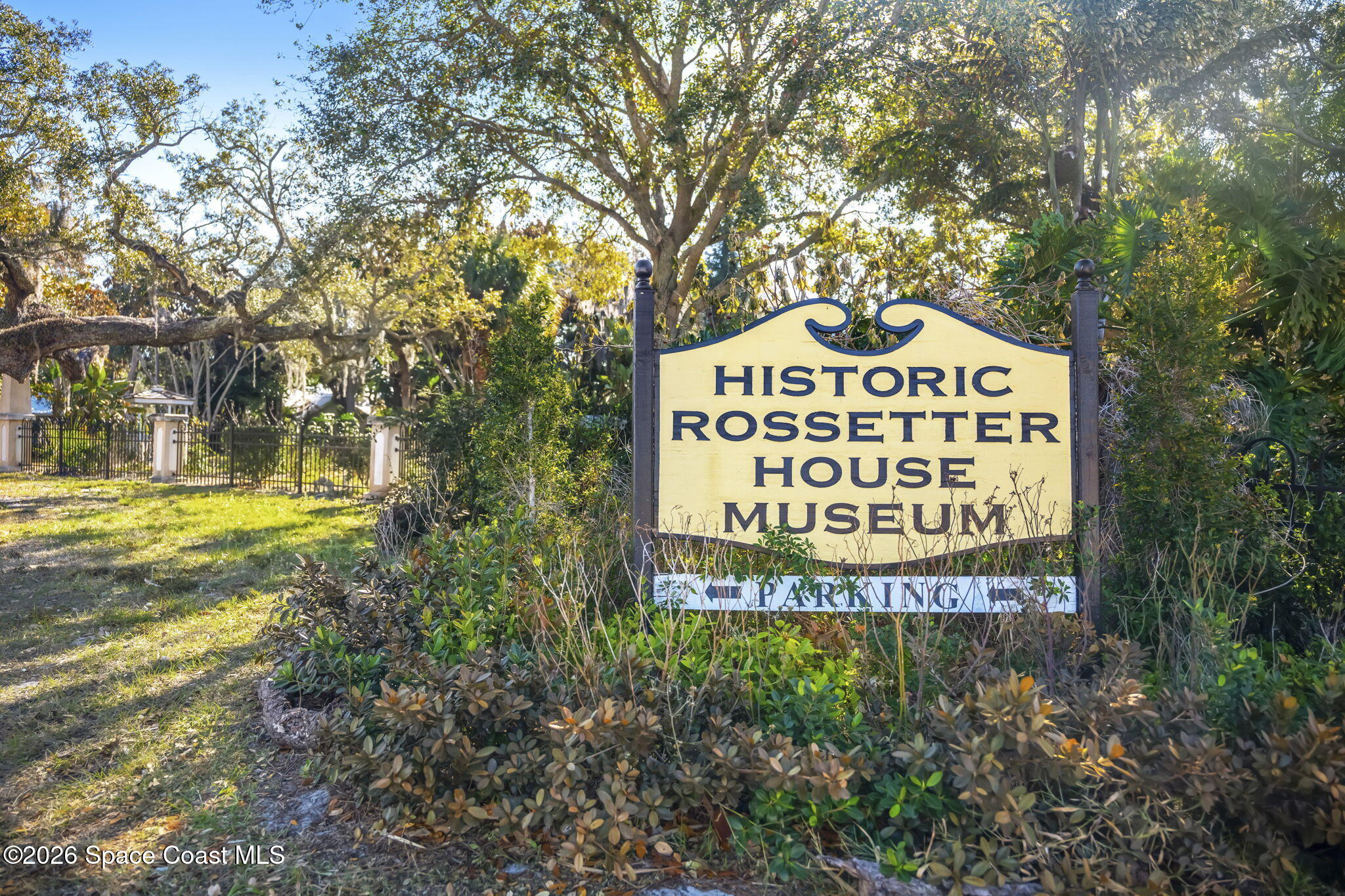 Historic Rossetter House Museum sign beside a shaded, fenced path.