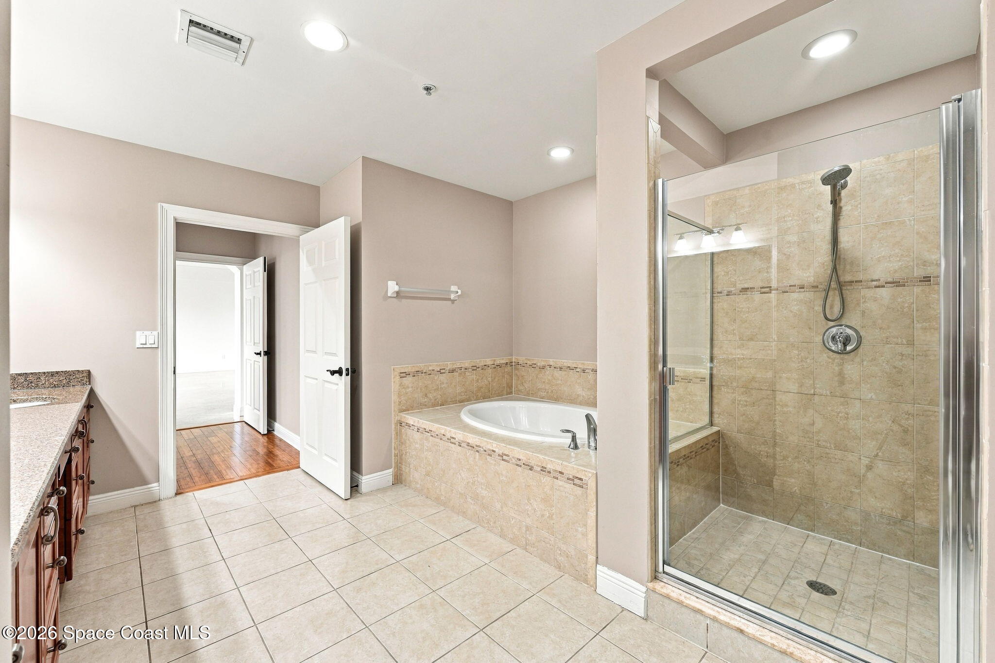 Bathroom with a glass-enclosed tiled shower, built-in soaking tub, and granite vanity counter.