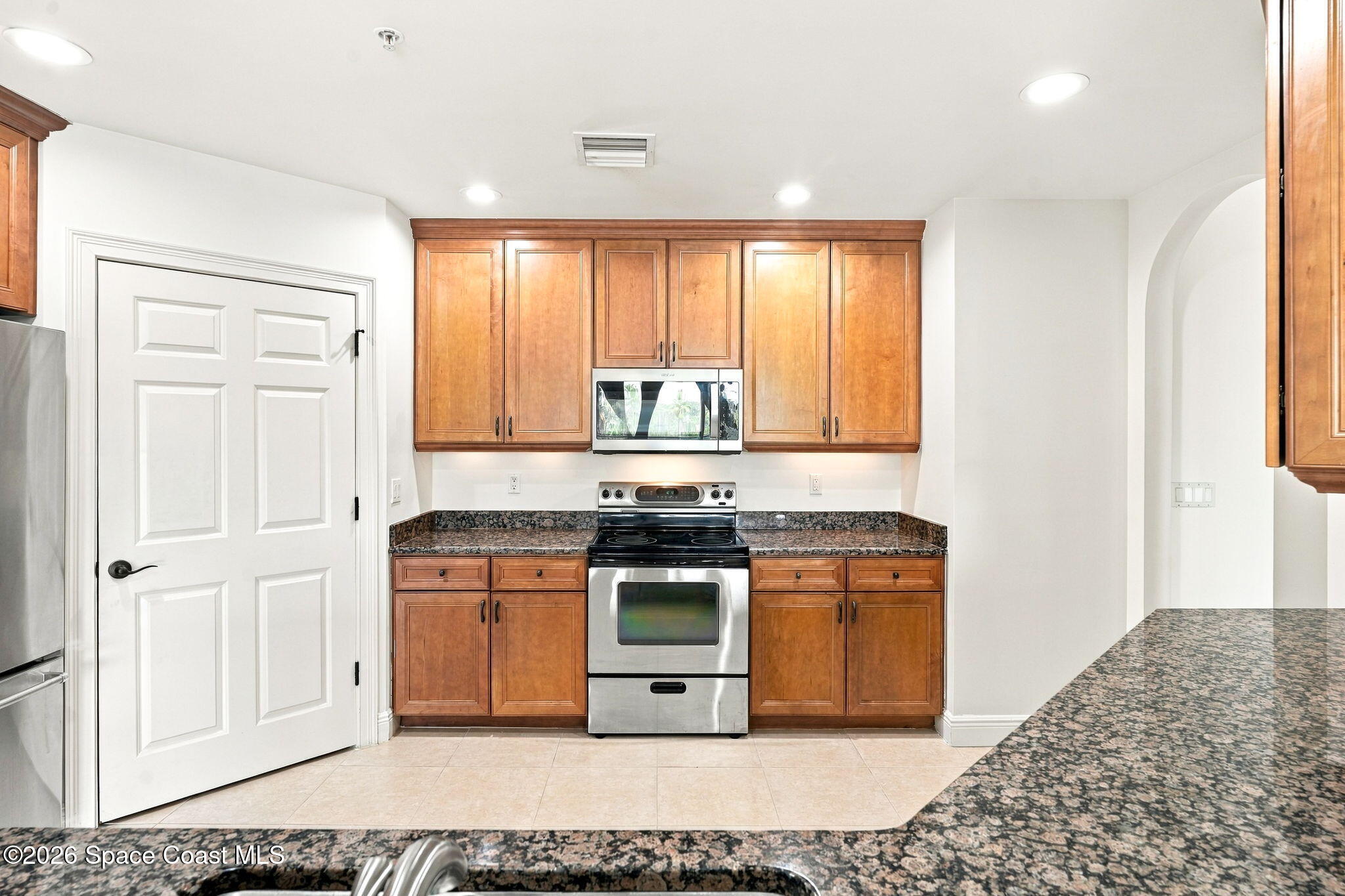 Kitchen with warm wood cabinets, granite counters, and a stainless steel range and microwave.