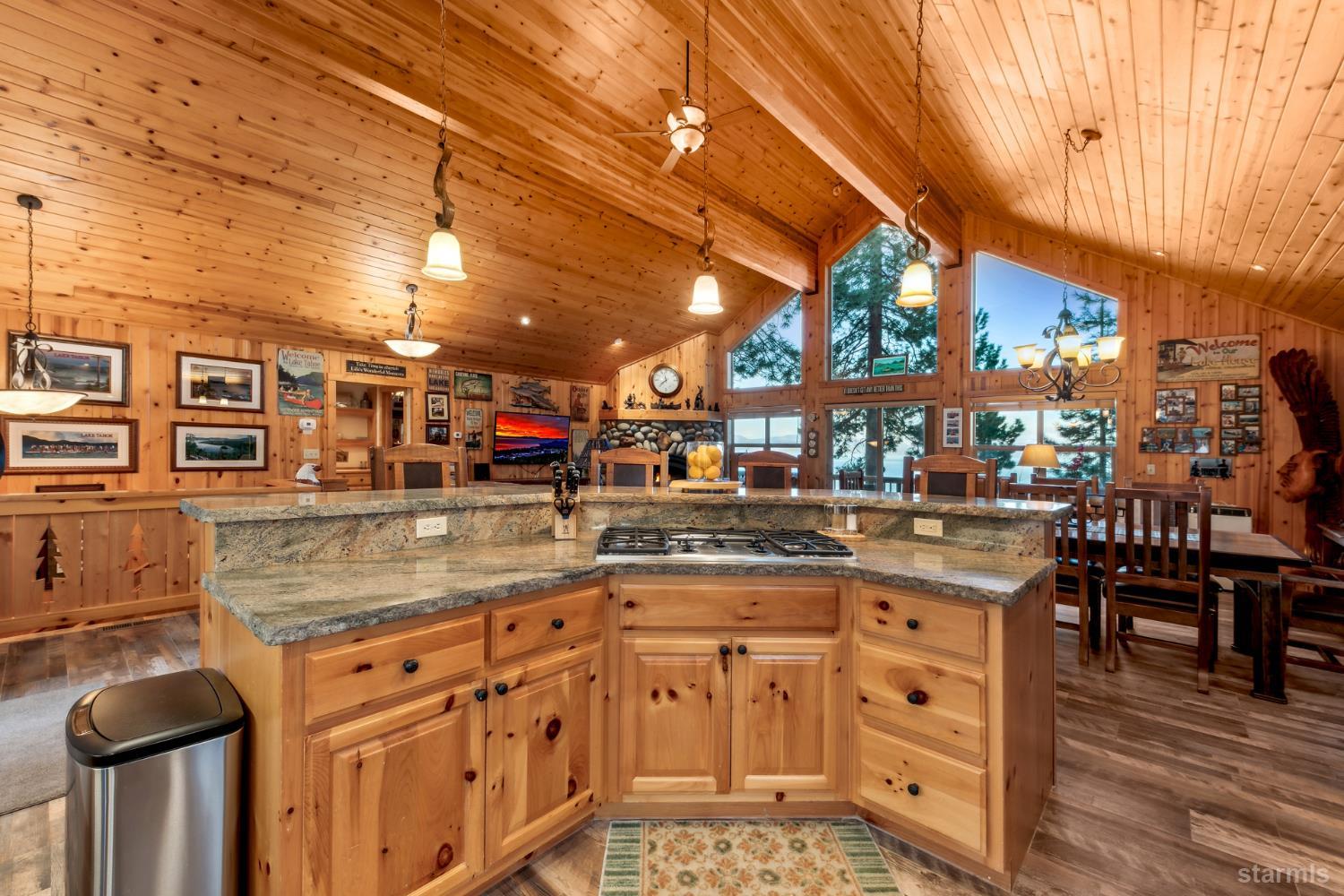 Wood-paneled kitchen with a granite cooktop island and lake views through tall windows.
