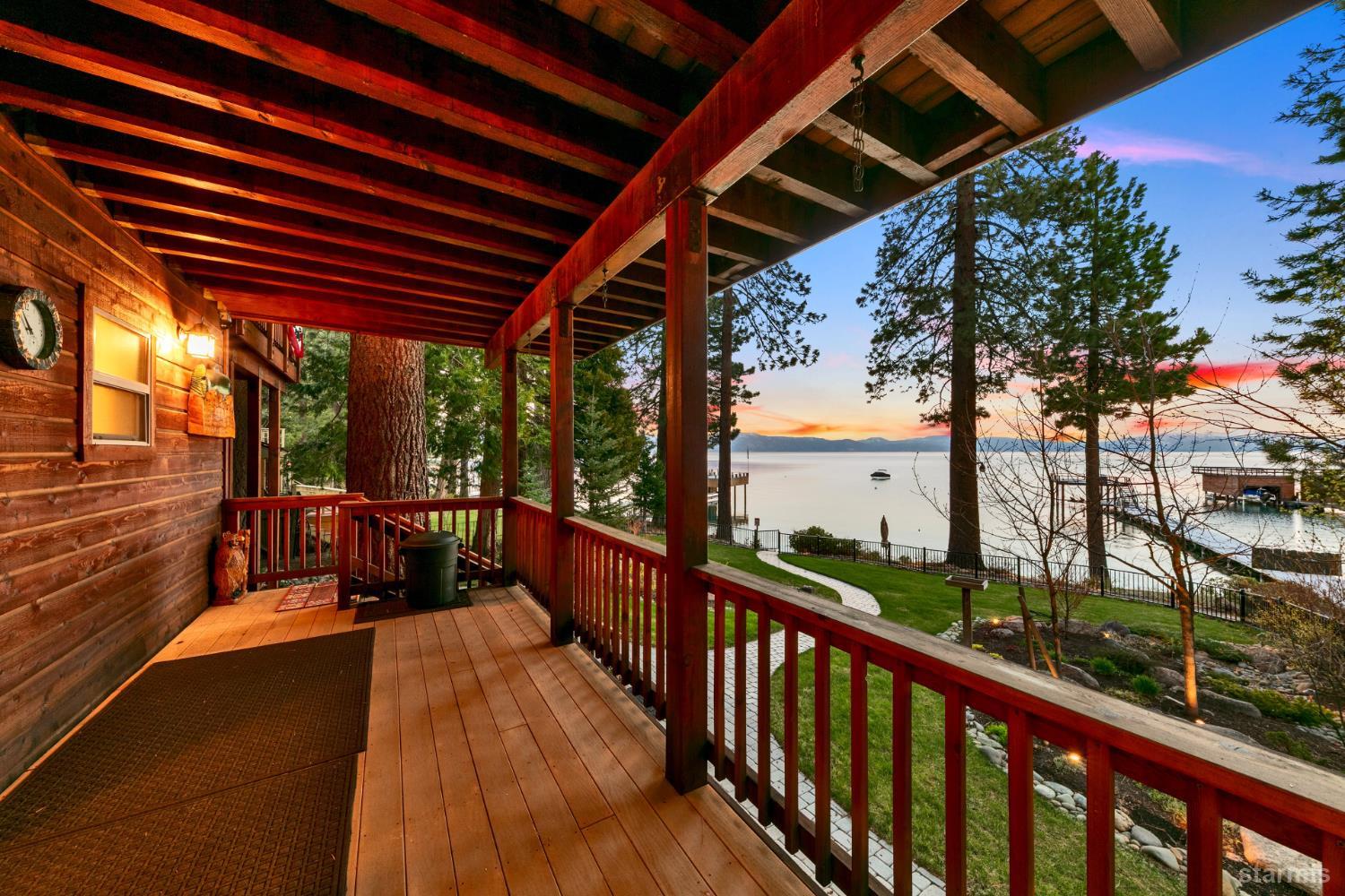 Covered wooden deck overlooking the lake and distant mountains at dusk.