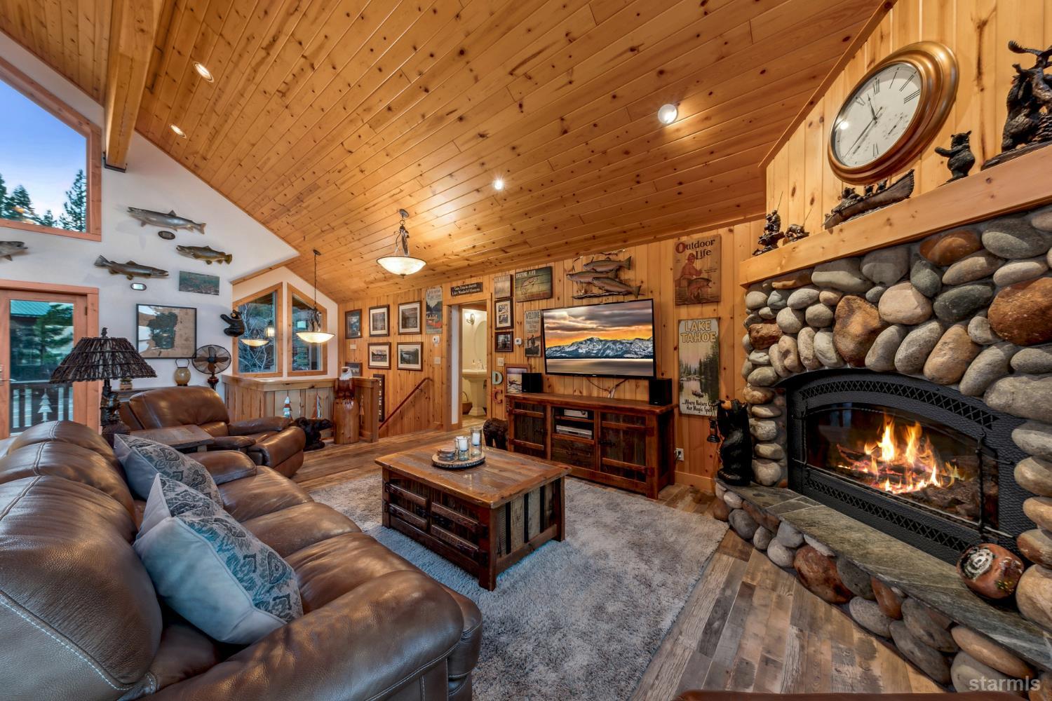 Living room with a vaulted wood ceiling, leather sofas, and a large stone fireplace.