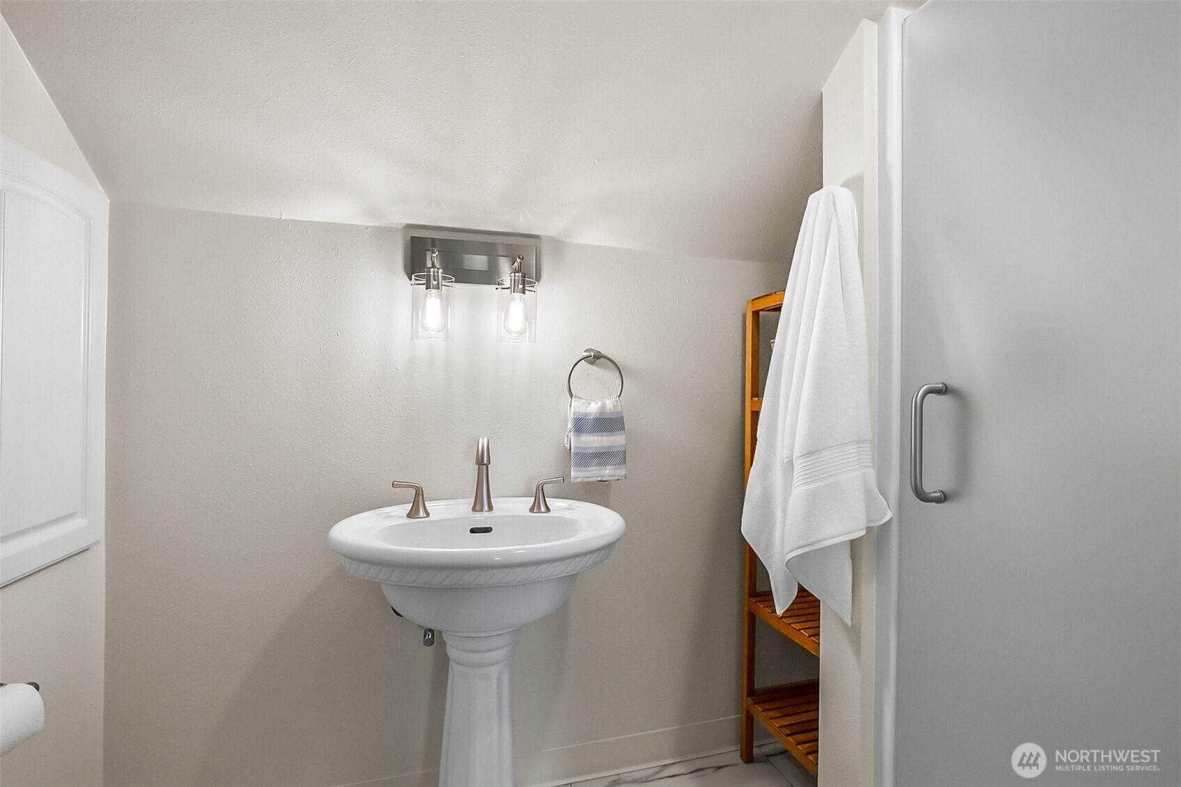 Bathroom with a white pedestal sink, brushed-metal faucet, and towels beside the shower.