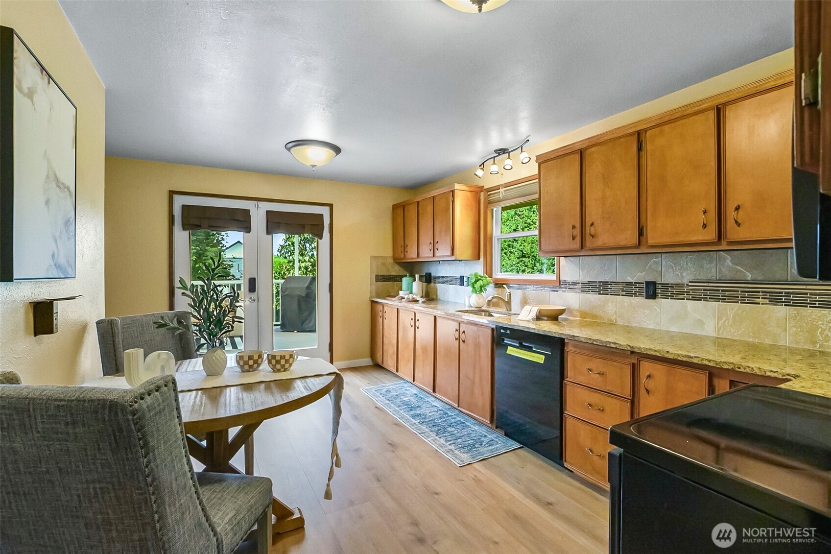 Kitchen with warm wood cabinets, tiled backsplash, and a dining table beside glass patio doors.